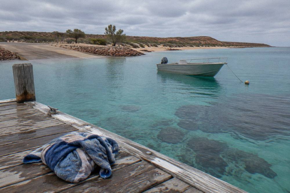 A small boat anchored over calm turquoise water near a coral reef