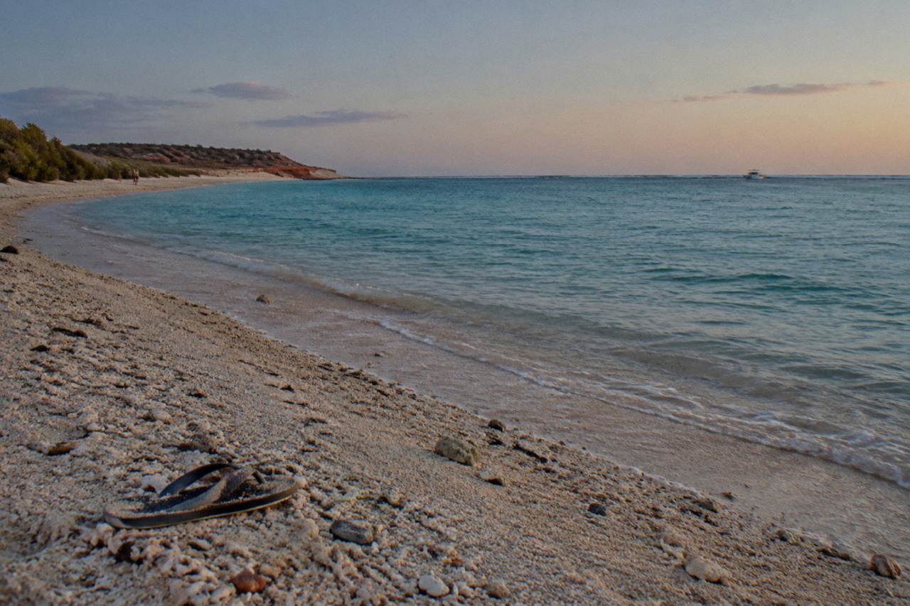 Calm turquoise water over a coral reef with a distant boat on the horizon