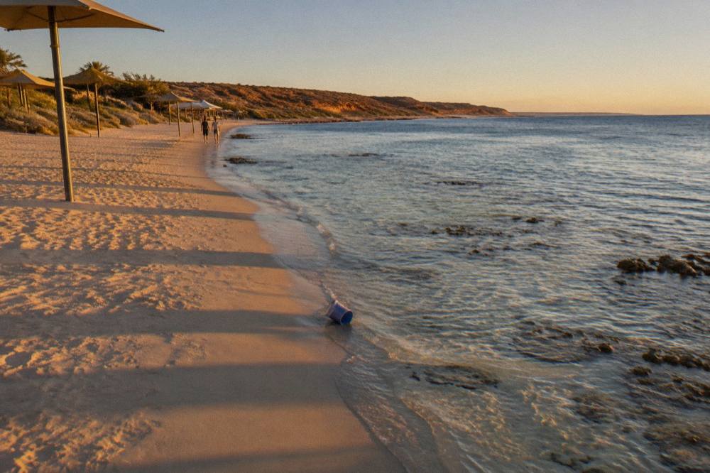 A calm sandy beach at Coral Bay with clear shallow water over coral