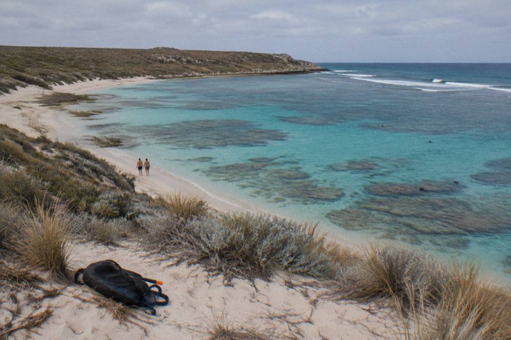 Shallow clear water over coral at Turquoise Bay with sandy beach and low dunes