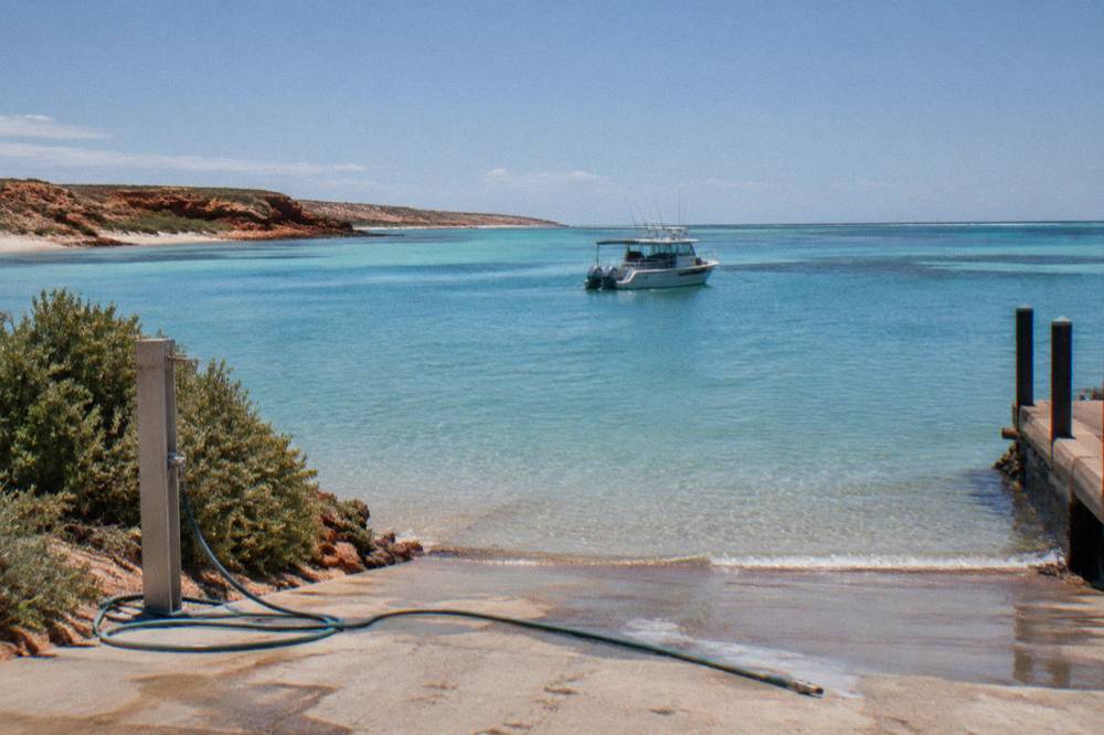 A small tour boat anchored over pale sand and clear reef water near Coral Bay