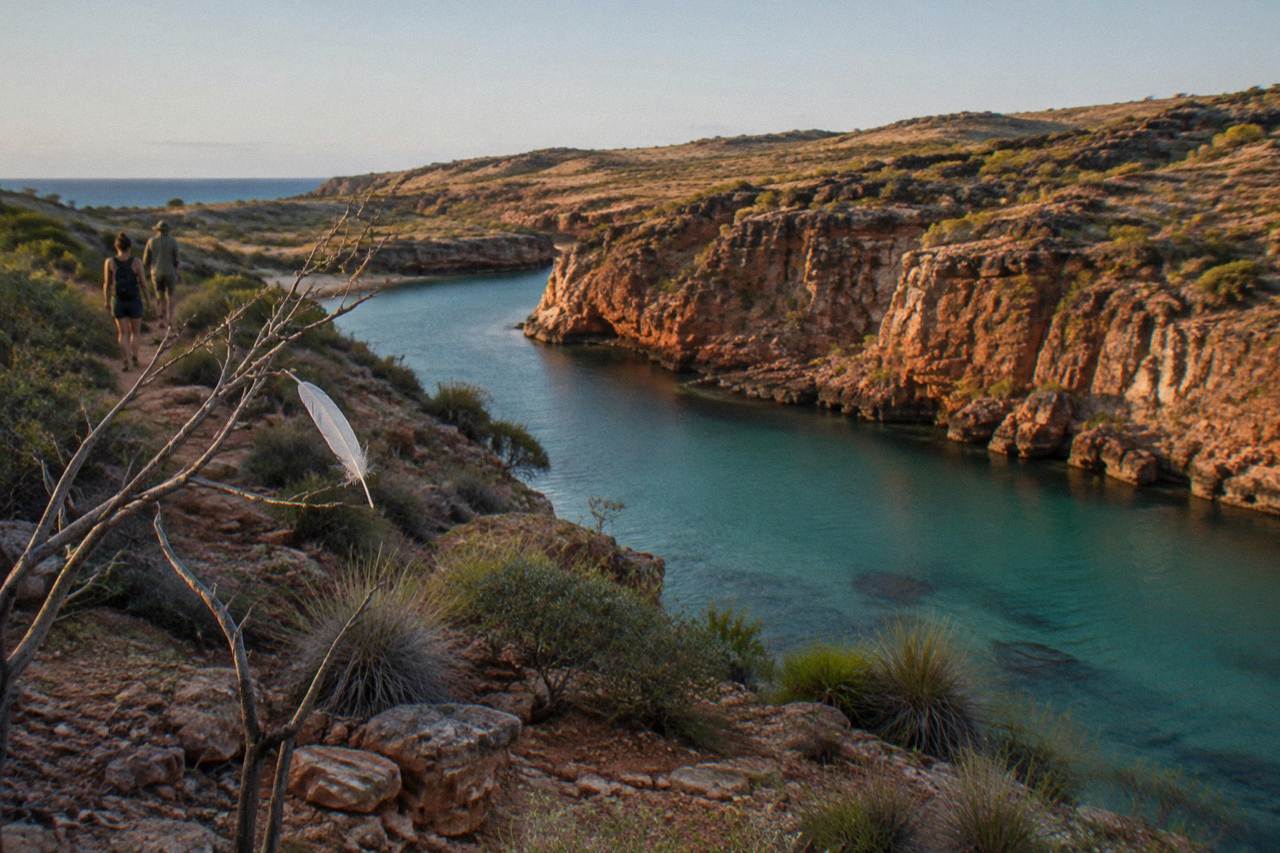 Turquoise shallows of Ningaloo Reef meeting a red desert headland under a clear sky