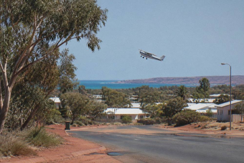 A spotter plane flying low over calm blue water near a reef coastline