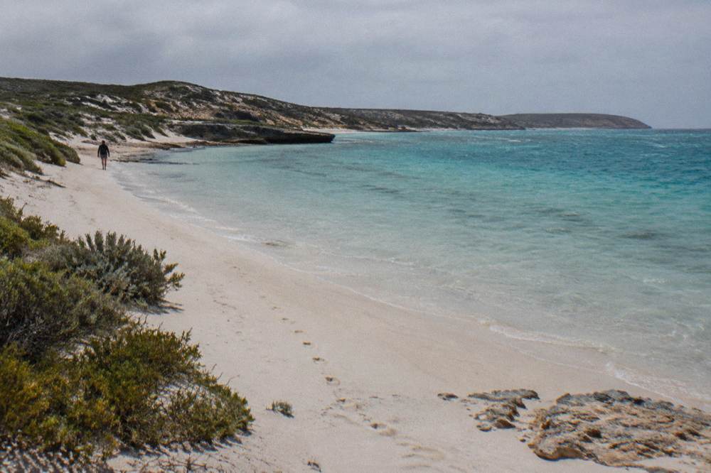 White sand beach at Turquoise Bay with clear shallow water and low dunes