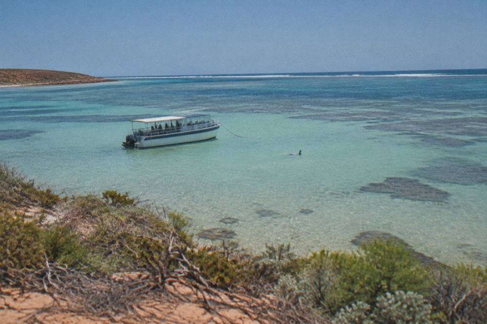 A tour boat anchored beside calm water inside Ningaloo Reef