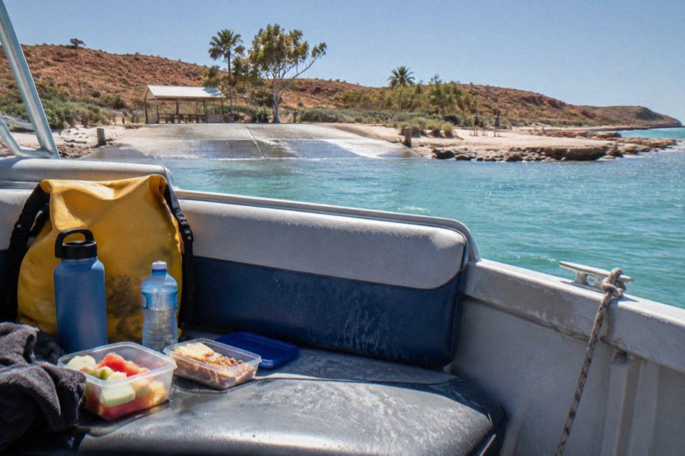 Water bottles, snack containers and a small dry bag packed on a boat bench seat