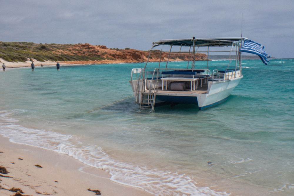 A soft day bag stowed under a bench on a tour boat with clear deck space around it