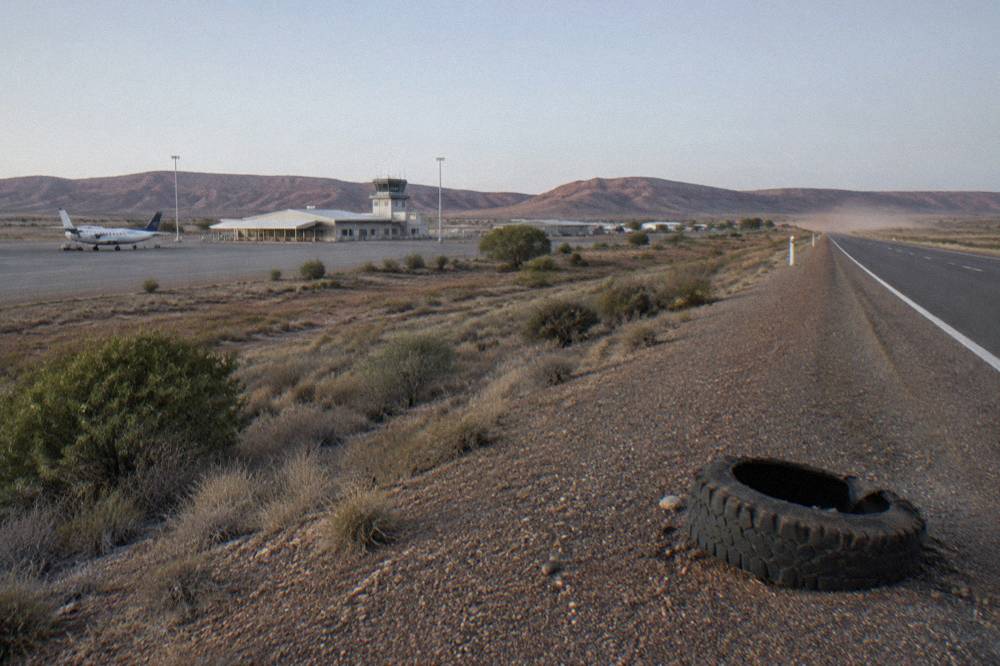 A sealed outback road running north through red Cape Range country toward Exmouth