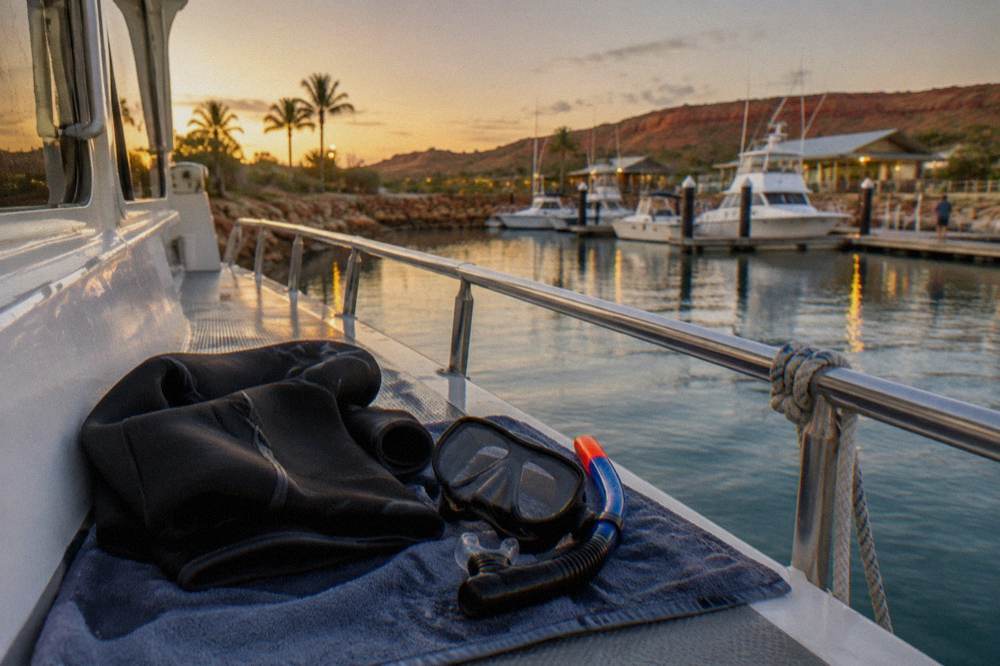 A folded wetsuit and snorkel gear laid out on a boat deck beside a towel