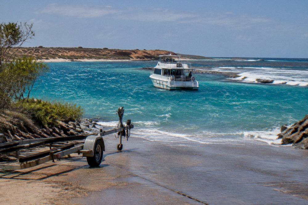 A tour boat anchored beside a coral reef ledge inside the Ningaloo lagoon