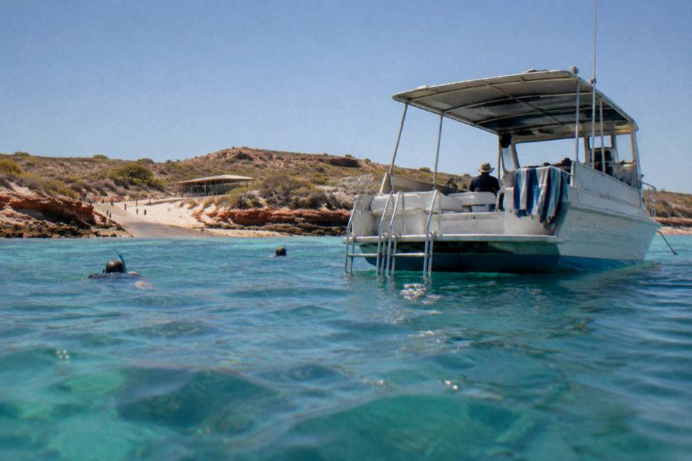 Snorkel boat anchored beside turquoise reef water inside Ningaloo Marine Park