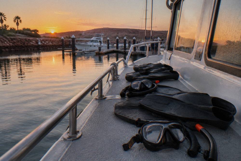 Snorkel masks and fins laid out on the deck of a boat in morning light