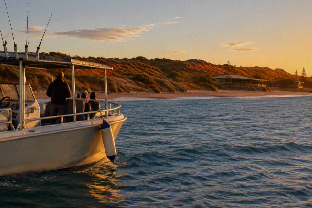 A small charter boat under golden evening light near the Exmouth coast