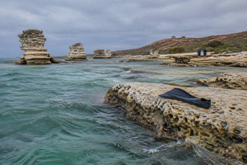 Limestone rock islets standing in clear water close to a sandy shoreline