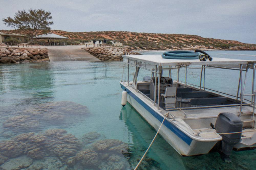A tour boat anchored beside a coral reef in calm blue water