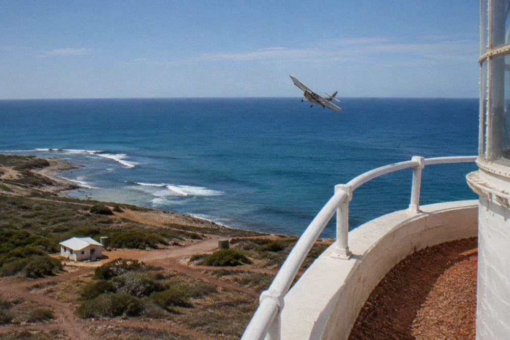 A spotter plane flying low over open ocean near a reef edge