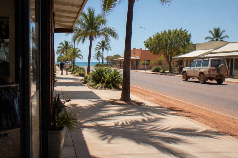 Palm-lined street in Exmouth town centre with low buildings and clear blue sky