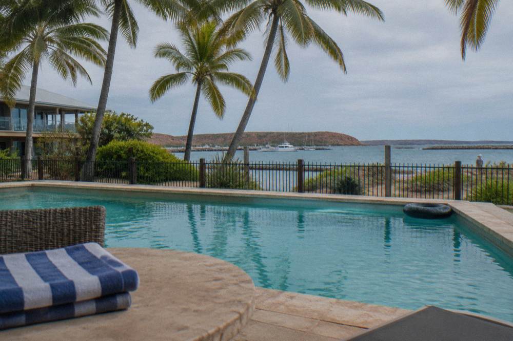 Resort swimming pool and palm trees overlooking calm marina water at Exmouth